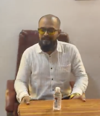 Man customers identify as Sumit Sudhir Choudhari seated at a desk in the reported office